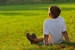 little boy sitting on grass